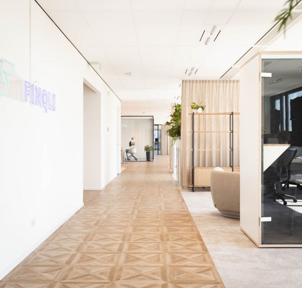 Modern kantoorinterieur op de Mt. Lincolnweg met houten vloer, glazen vergaderruimtes en het Finqle-logo aan de muur.